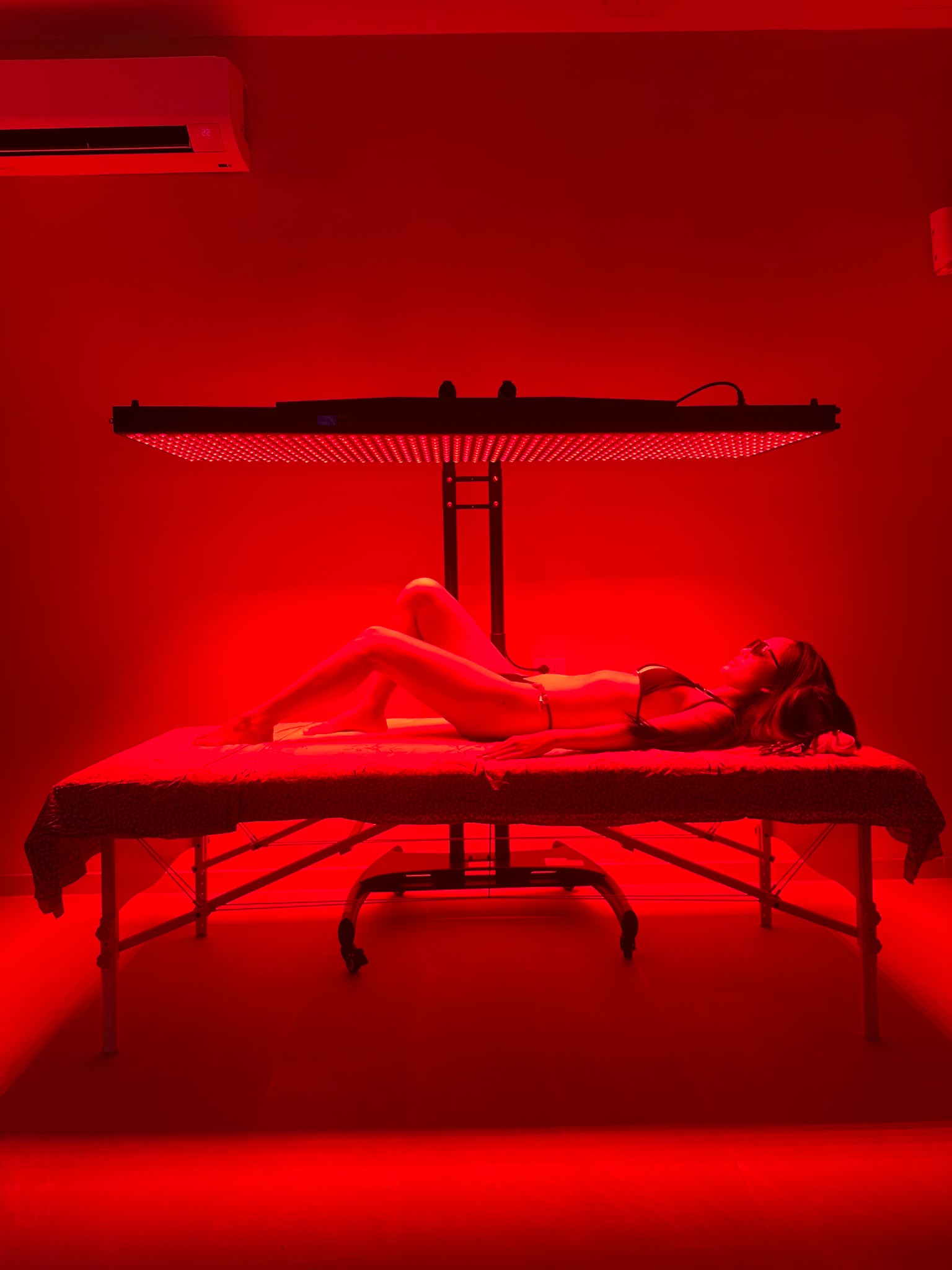 Guest reclining beneath the red light therapy panel at BREATHE Phuket
